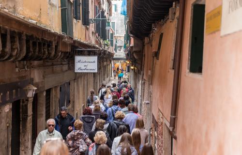 People squeeze down a narrow street in Venice