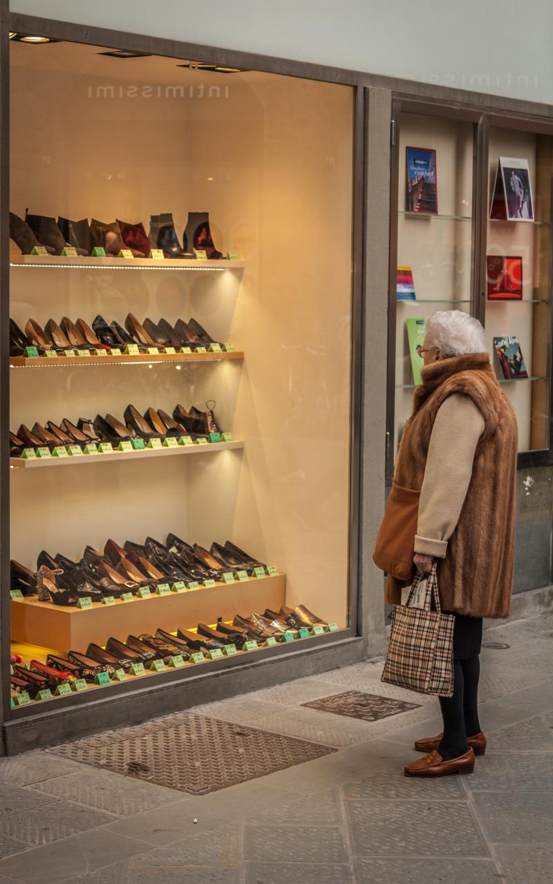 Older Italian woman looks at a store display of shoes