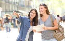 Happy girl helping to a tourist who asks direction in the street