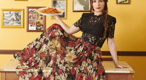 Woman sitting on a trattoria table in Rome holding a plate of pasta