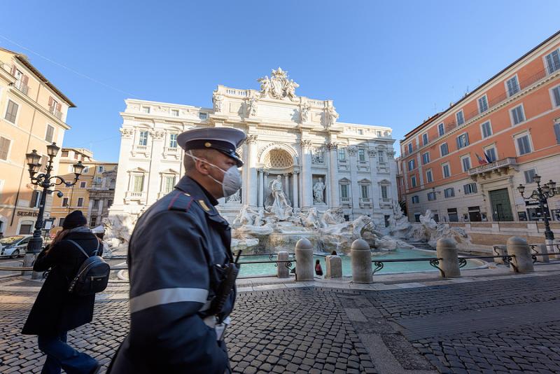 Policeman with face mask in front of Trevi fountain in Rome