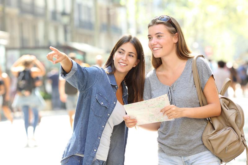 Happy girl helping to a tourist who asks direction in the street Happy girl helping to a tourist who asks direction in the street