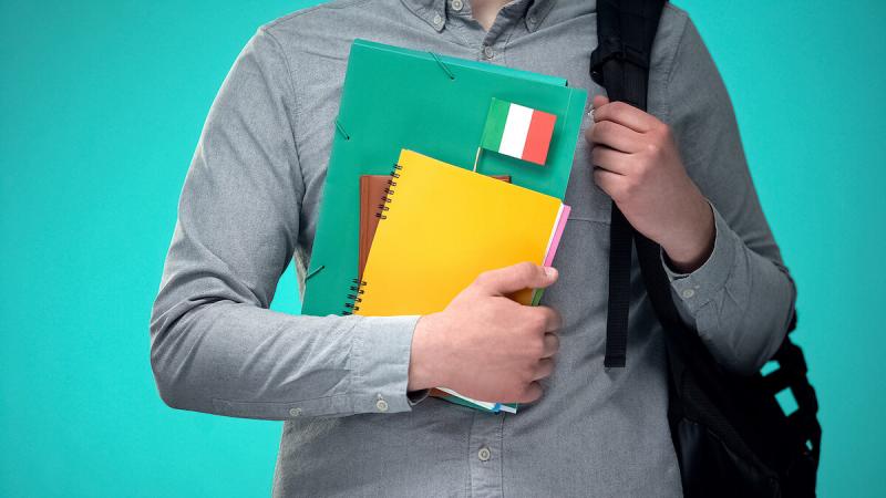 Student holding notebooks with Italian flag, international educational program