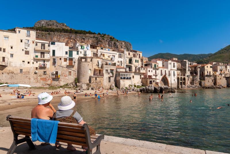 An elderly couple on the waterfront of Cefalu, Sicily / Photo: Alex Segre via Shutterstock