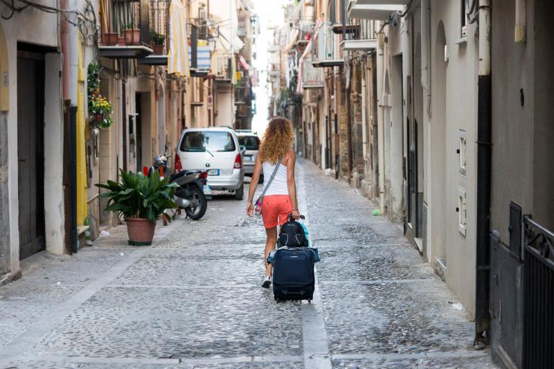 Woman wheels suitcase through streets of Cefalu
