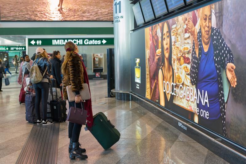 Travelers at Milan Malpensa airport look at a departures board